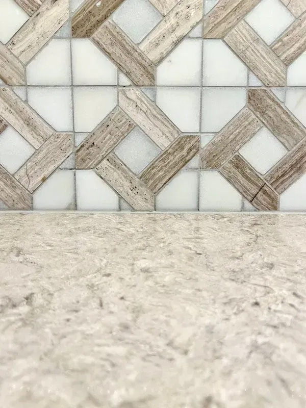A close up of a mosaic tile wall with a counter top in the background.