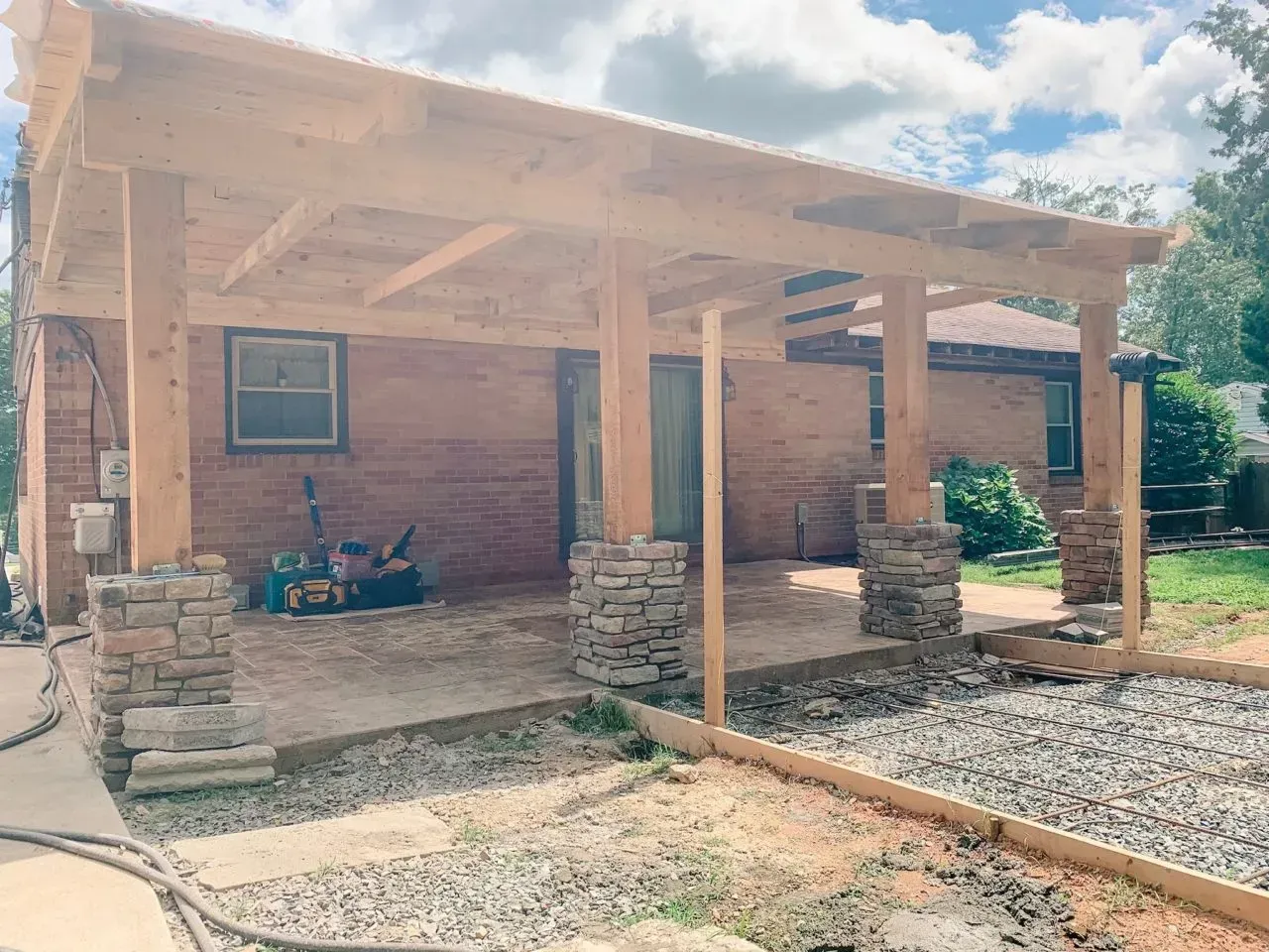 A wooden porch is being built on the side of a brick house.