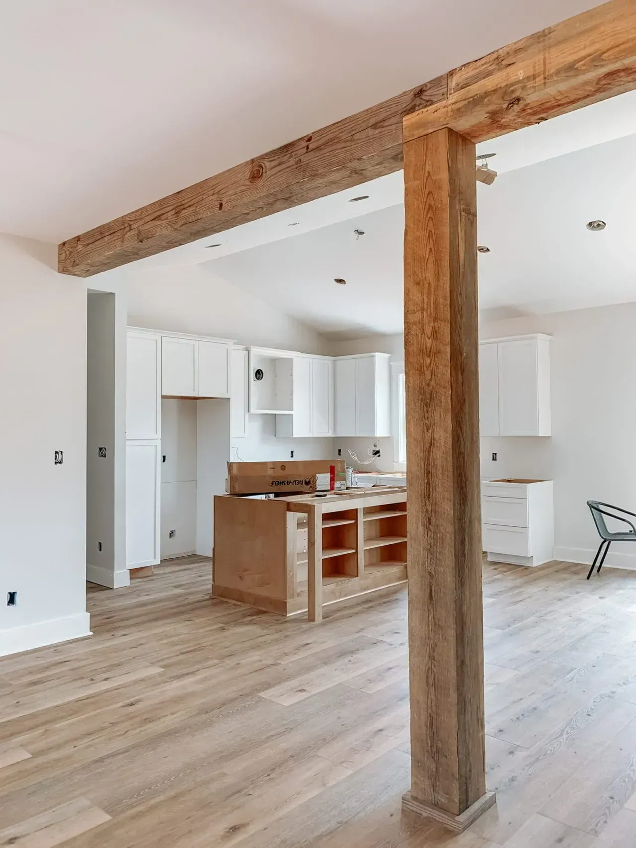 A kitchen with a wooden beam between the kitchen and living room