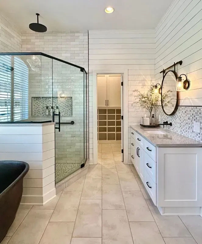 A bathroom with a tub , sink , shower and mirror.