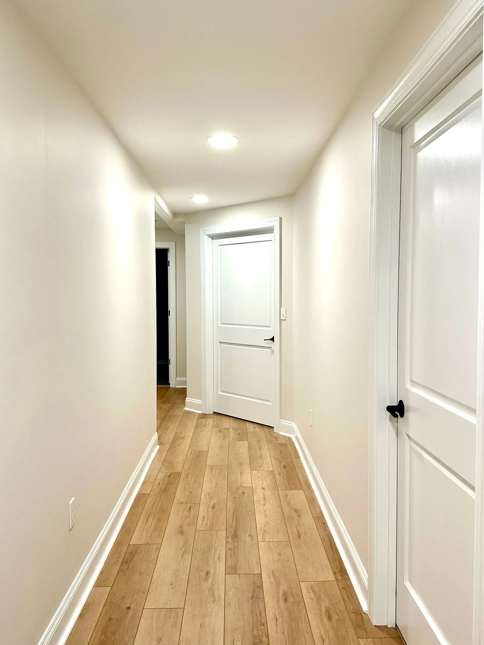 A long hallway with hardwood floors and white walls.