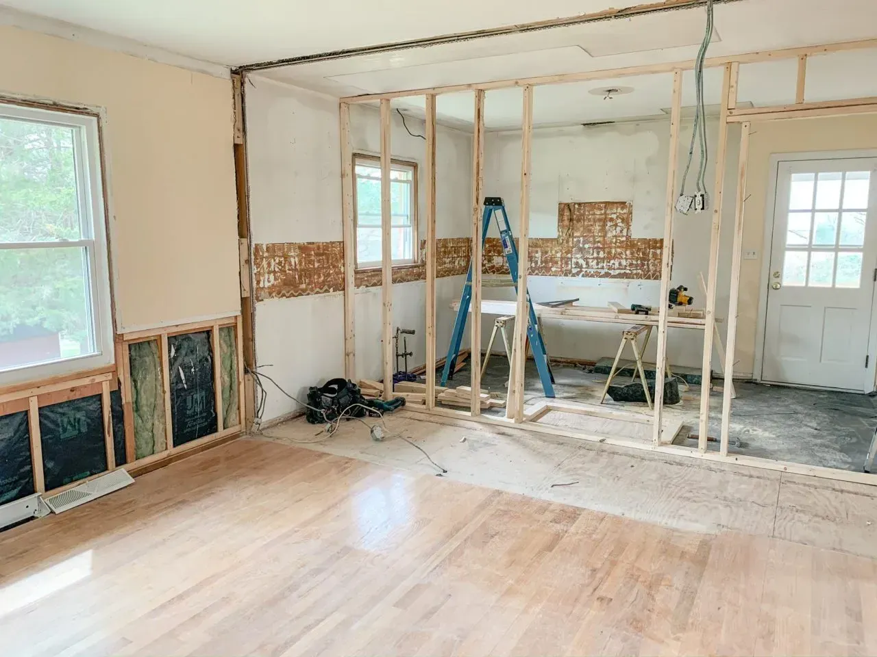 A room with a wooden floor and a ladder in it is being remodeled.