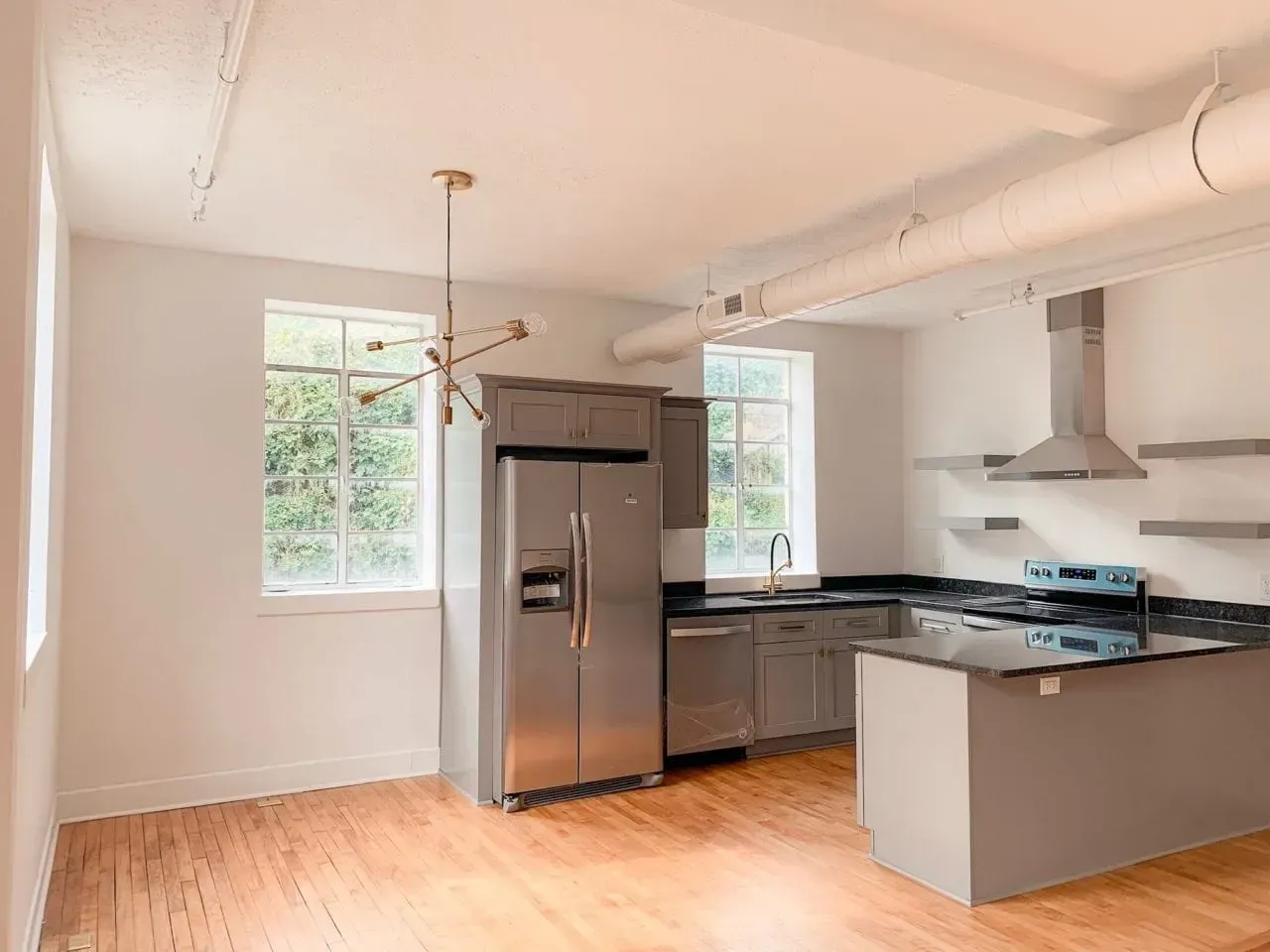 An empty kitchen with stainless steel appliances and a large island.