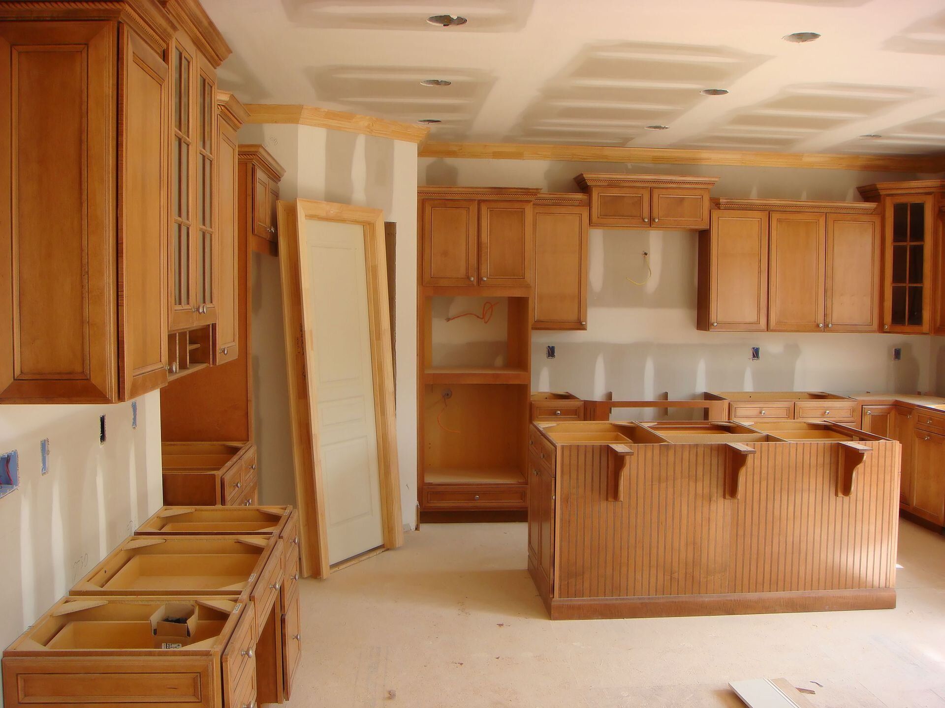 A kitchen under construction with wooden cabinets and a large island