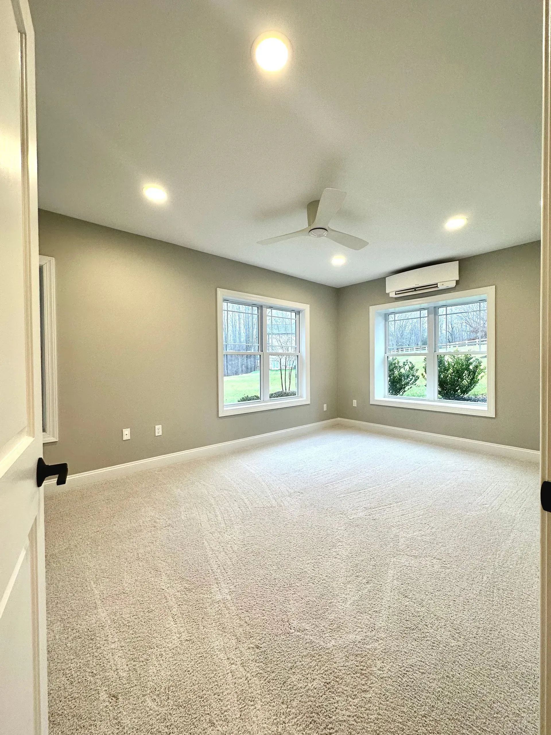 A large empty room with a ceiling fan and a lot of windows.
