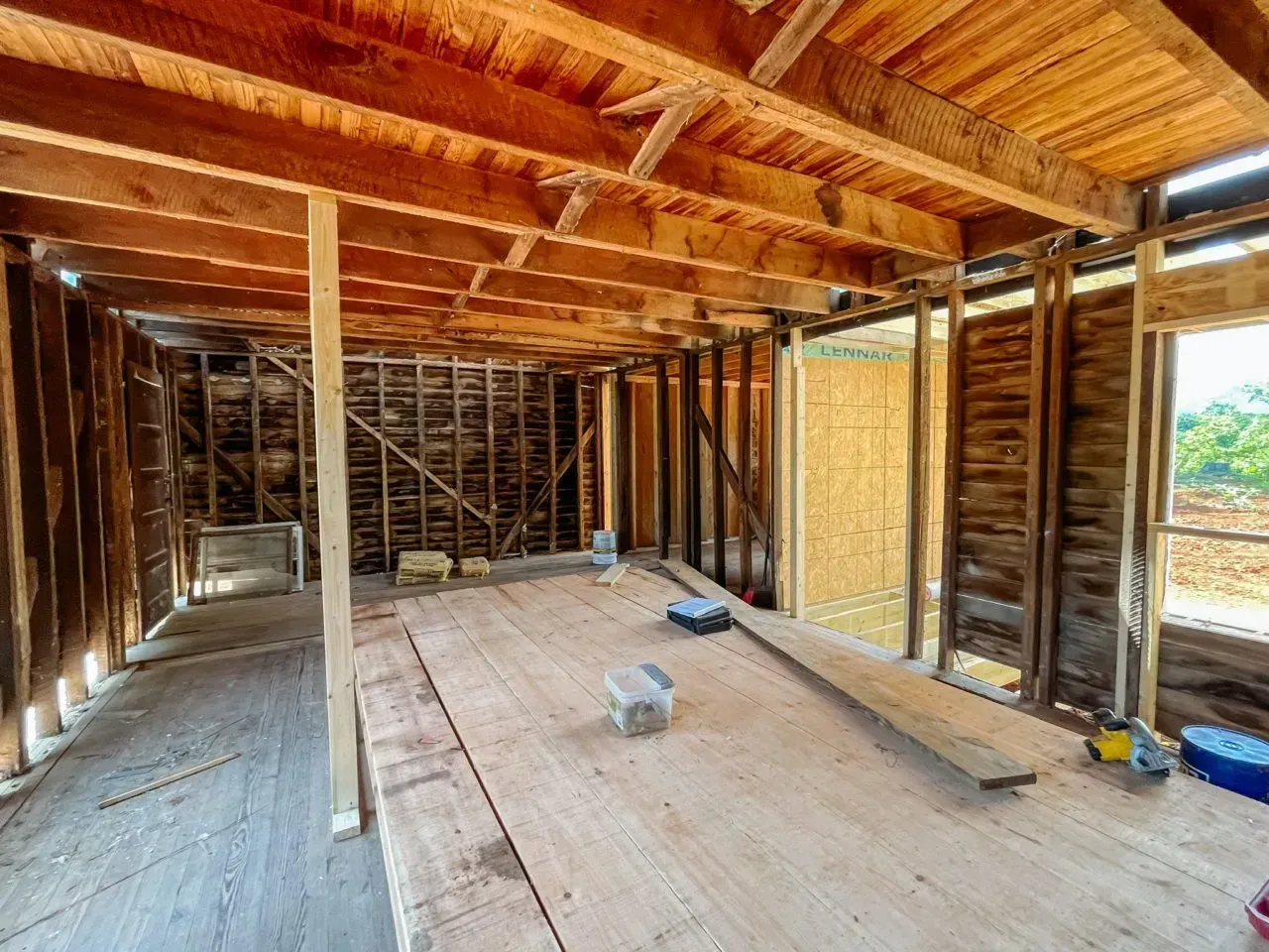 A room in a house under construction with wooden beams and a wooden floor.