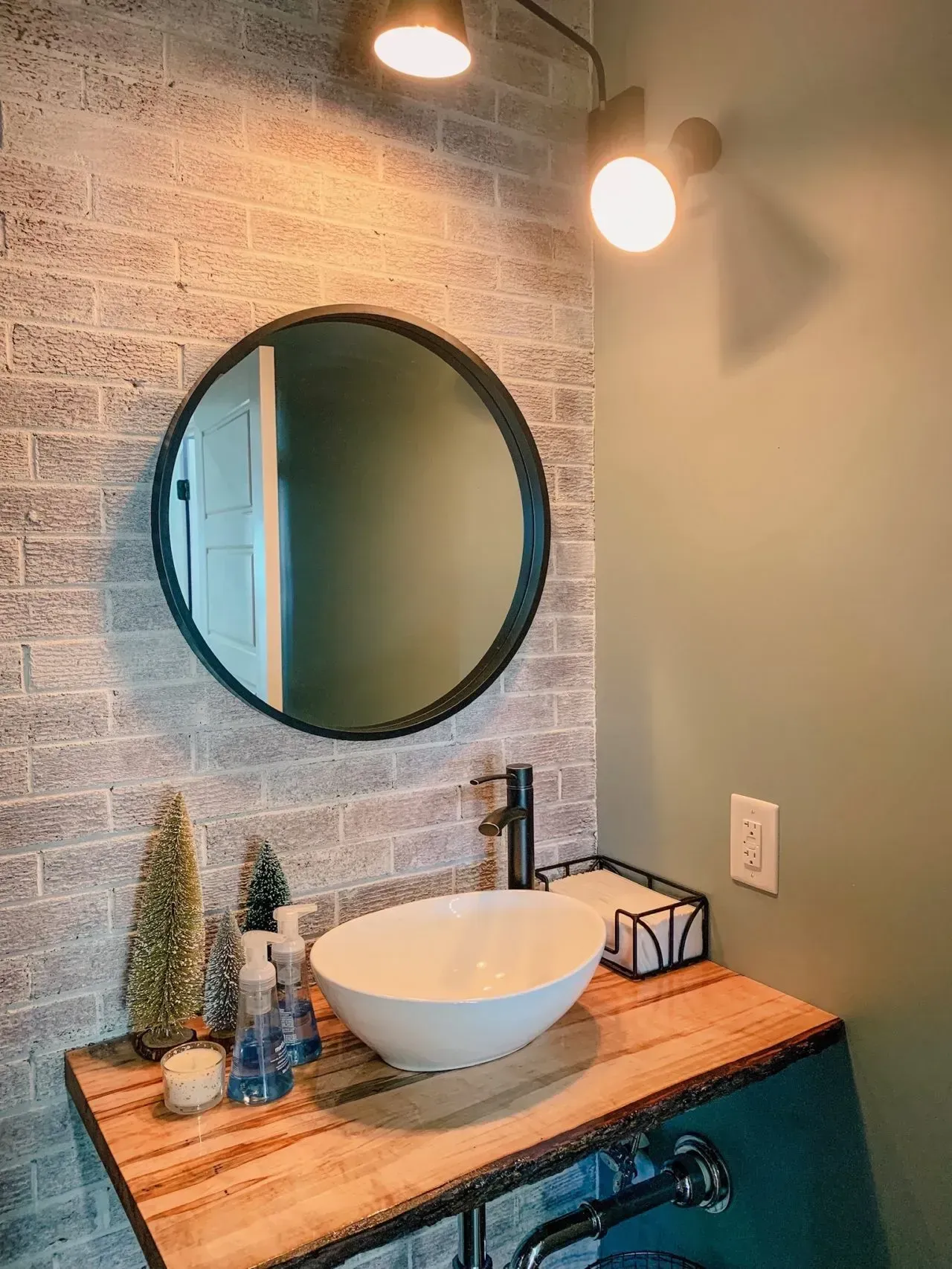 A bathroom sink with a round mirror and a wooden counter top.