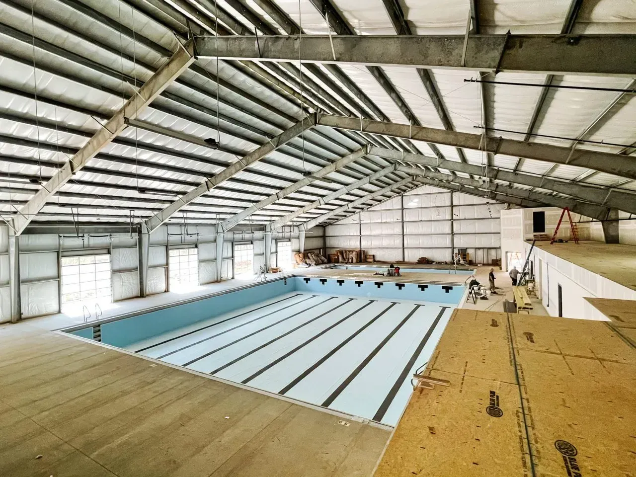 A large indoor swimming pool is being built in a large building.