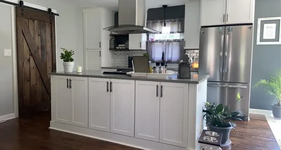 A kitchen with white cabinets and a sliding barn door.