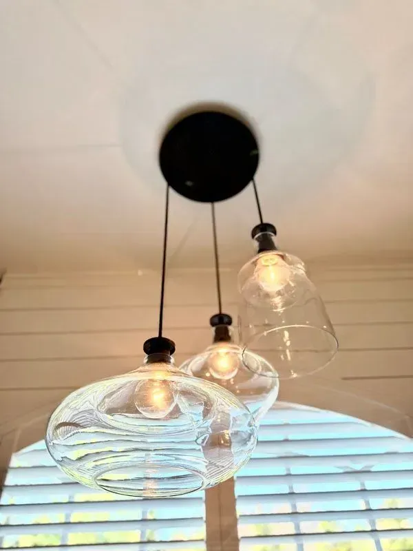 A ceiling light with three clear glass shades hanging from it.
