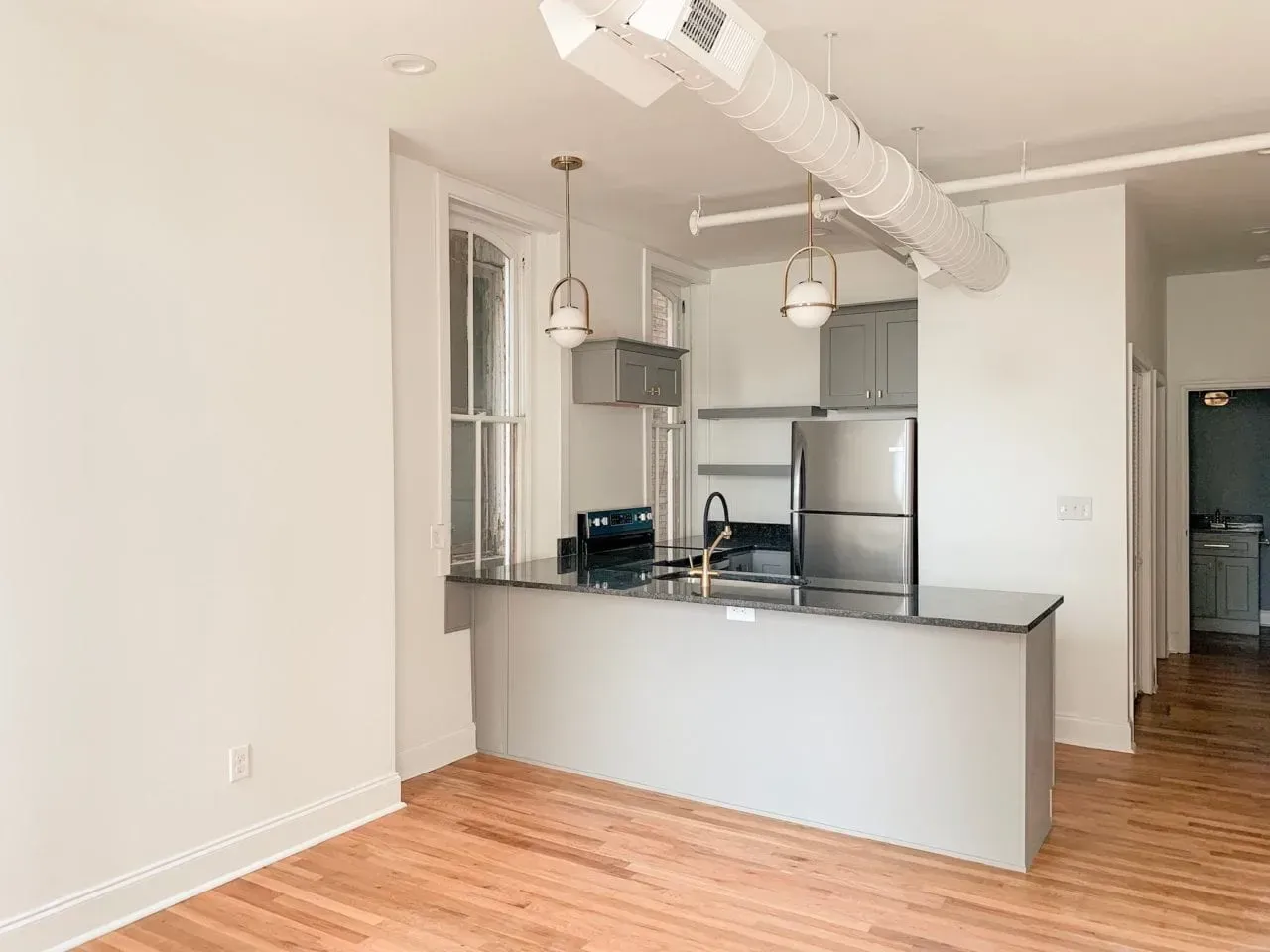 An empty kitchen with a stainless steel refrigerator , stove , and sink.