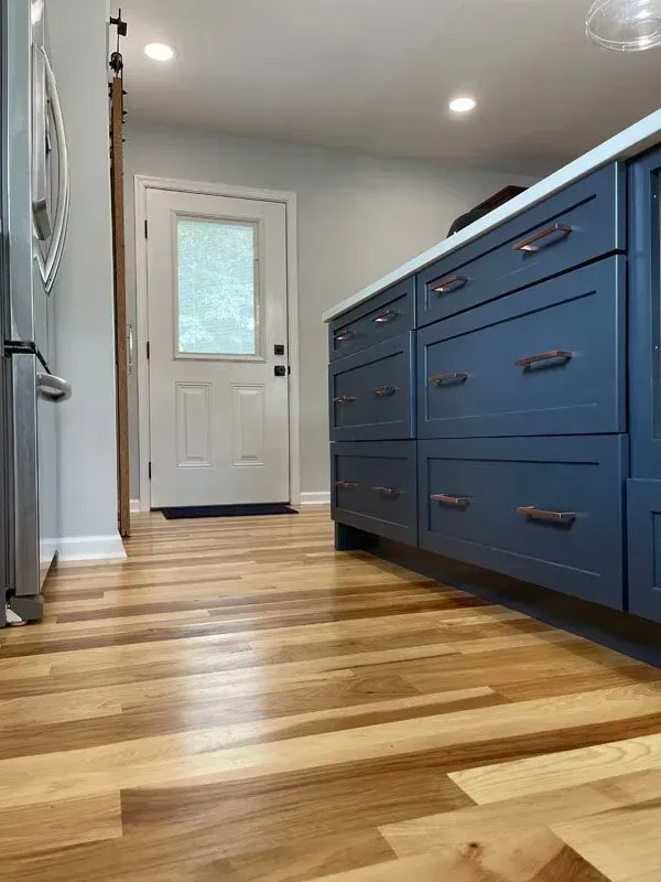 A kitchen with blue cabinets and hardwood floors.
