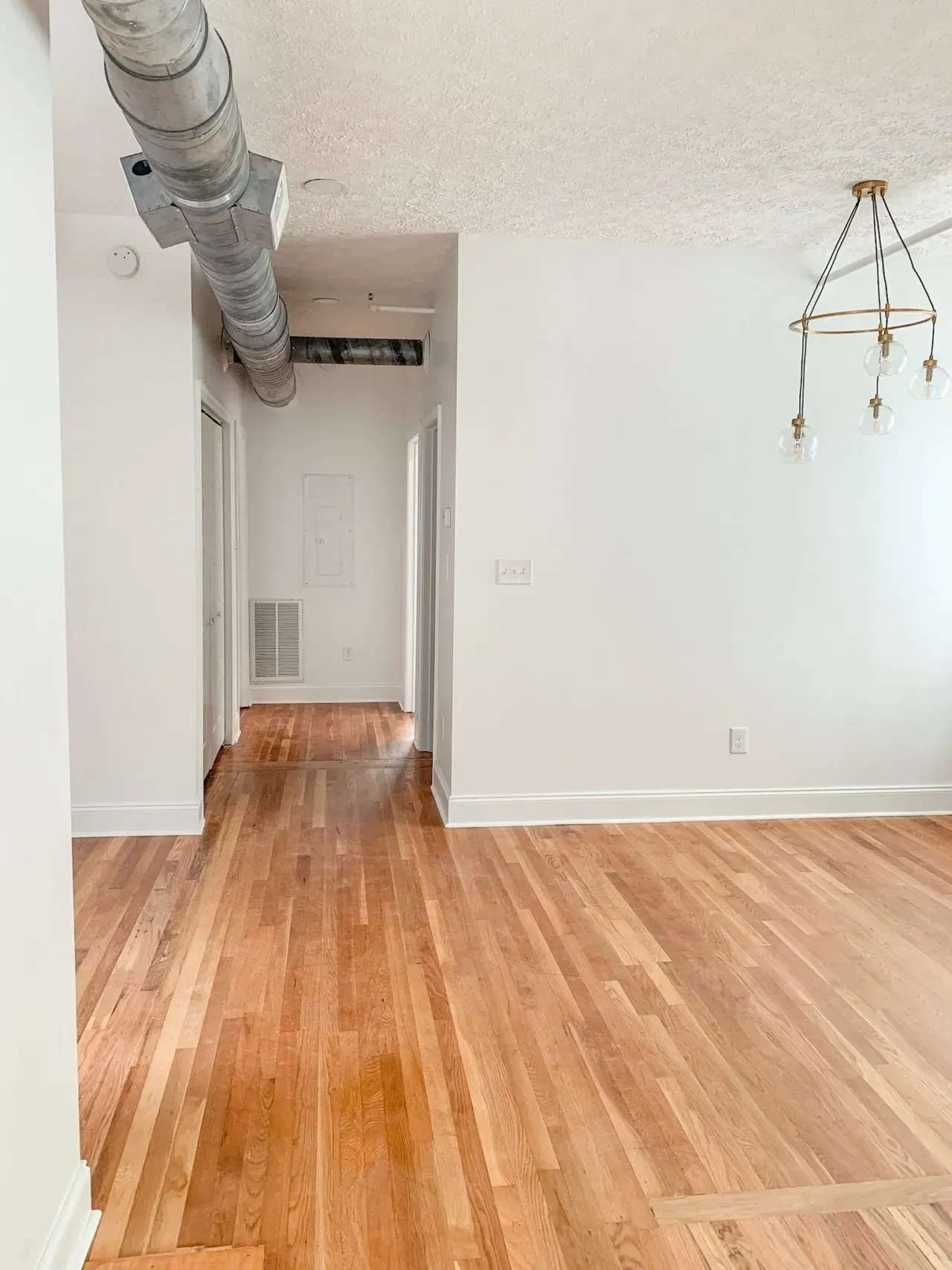An empty room with hardwood floors and white walls.