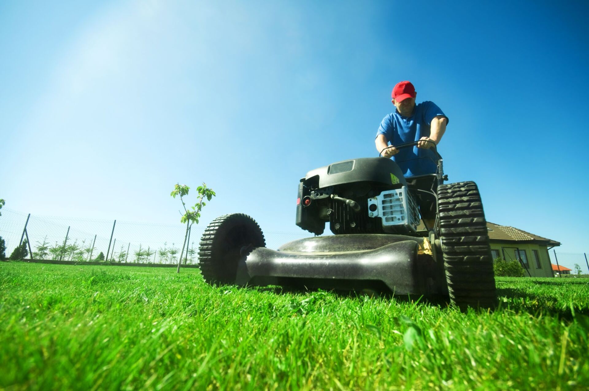 A man is riding a lawn mower on a lush green field.