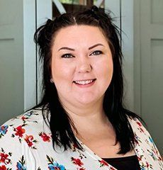 A woman in a floral shirt is smiling for the camera.