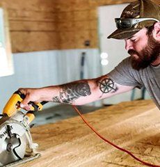 A man is using a circular saw to cut a piece of wood.