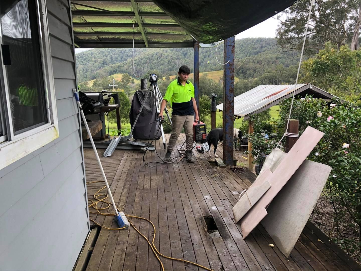 Person on a Wooden Deck, Next to a House, Holding Tools — Alcando Renovations and Maintenance In Wingham, NSW