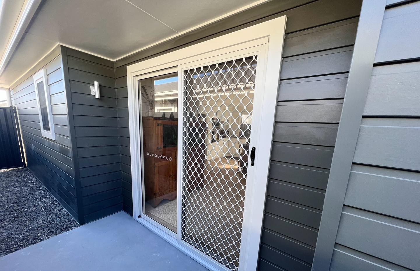 Sliding Screen Door With Security Mesh, Grey Siding, and Concrete Patio — Alcando Renovations and Maintenance in Bobin, NSW