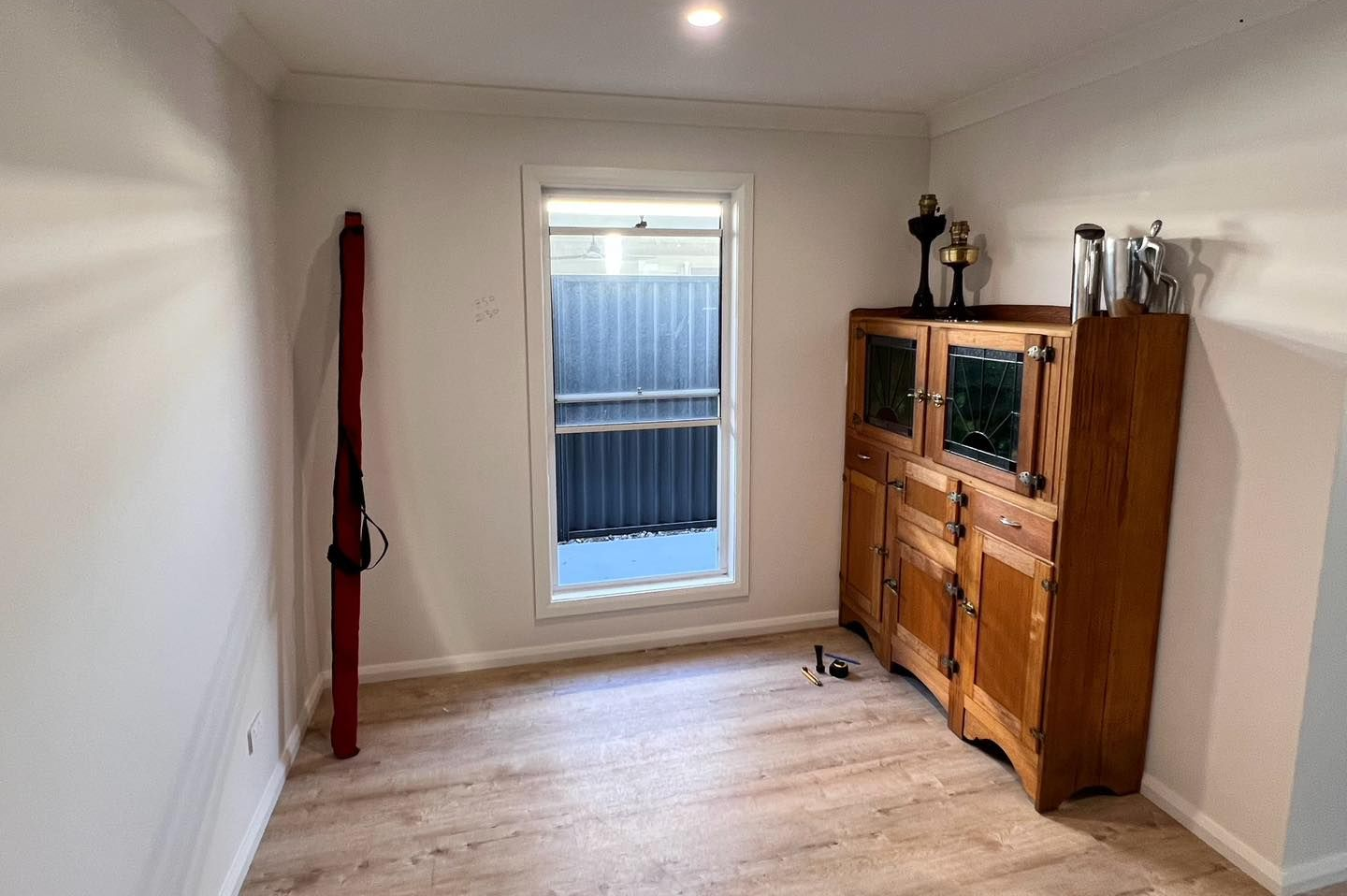 Empty Room With Window, Wood Cabinet, Fishing Rod Leaning Against Wall — Alcando Renovations and Maintenance In Bobin, NSW
