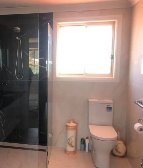 Bathroom With Black Tiled Shower, White Toilet, and Window — Alcando Renovations and Maintenance In Harrington, NSW