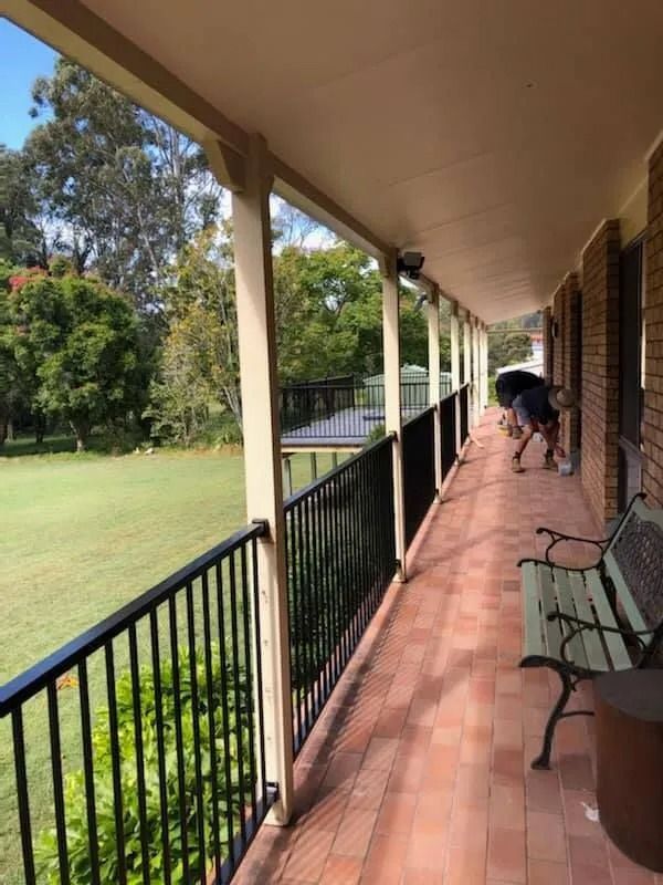 Long Outdoor Veranda With Black Railing, Red Brick Floor, and Green Yard — Alcando Renovations and Maintenance In Bobin, NSW