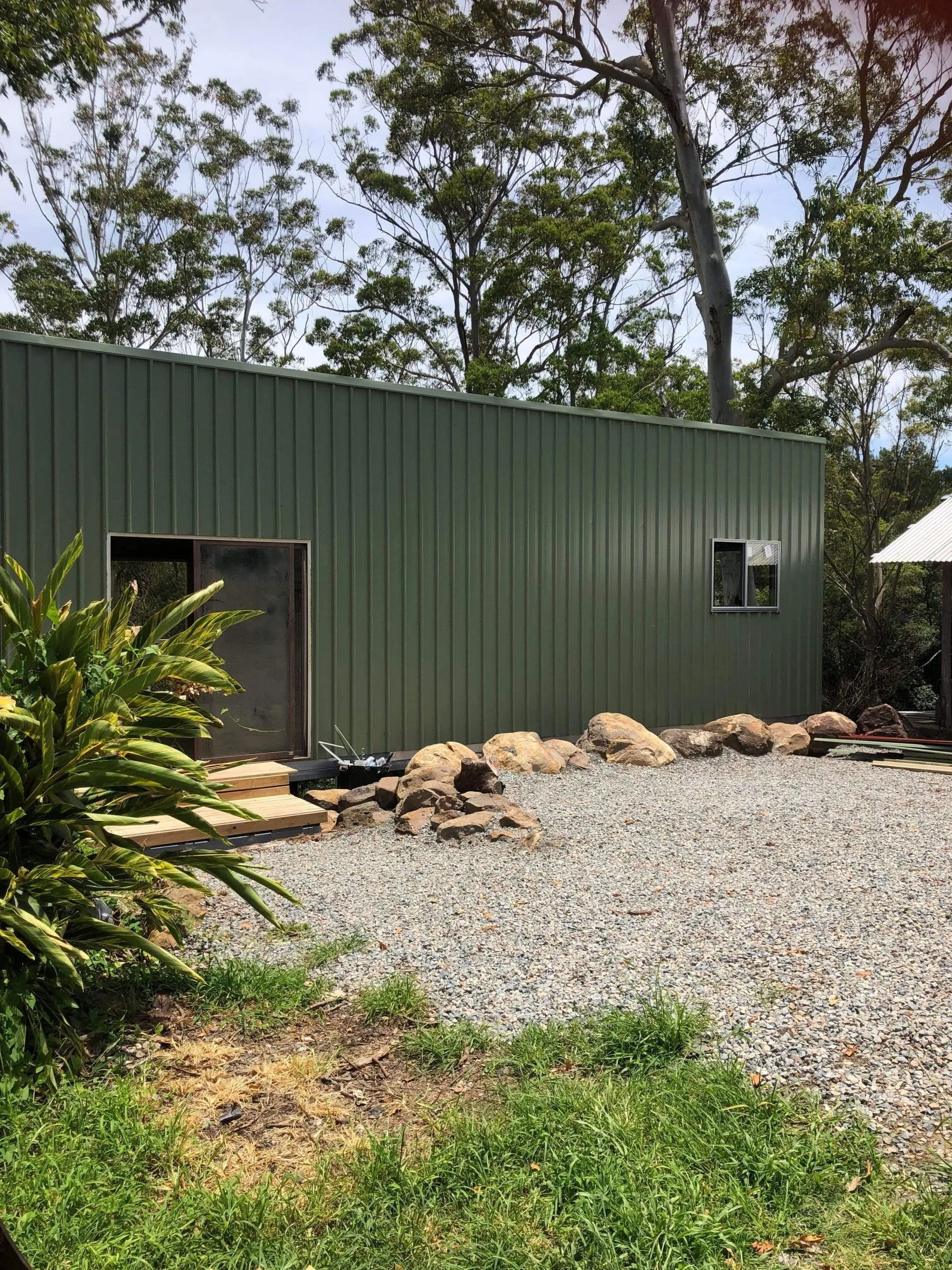 Green Metal Shed With a Doorway, Window, and Rock Landscaping — Alcando Renovations and Maintenance In Bobin, NSW