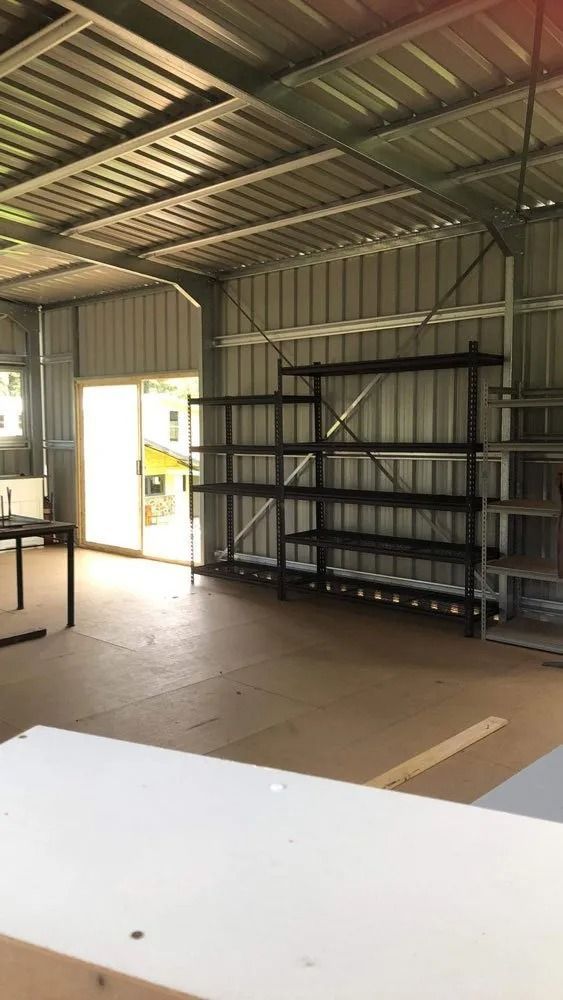 Empty Metal Shed Interior With Shelving and a Sliding Glass Door — Alcando Renovations and Maintenance In Bobin, NSW