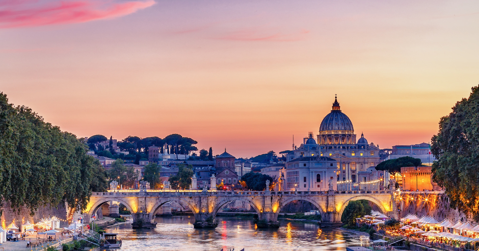 Sunset view of St. Peter’s Basilica and the Tiber River with illuminated bridges in Rome