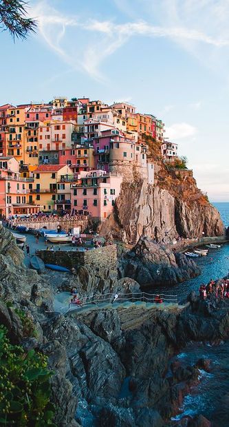 Colorful cliffside village with pastel buildings overlooking a rocky seaside cove at sunset