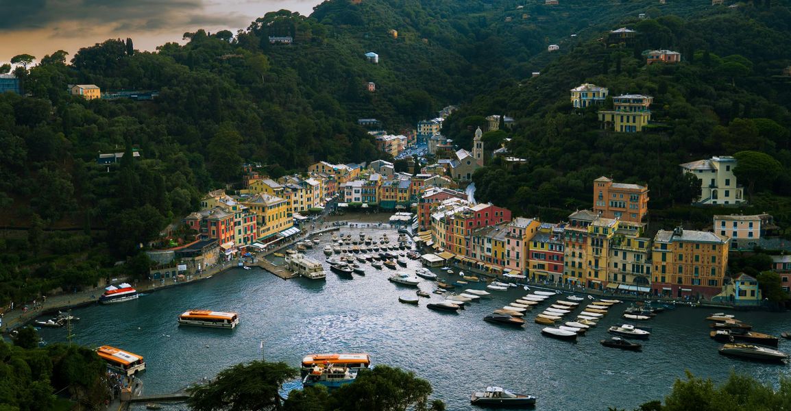 Harbor town with colorful buildings, boats, and hillside greenery along a sheltered bay