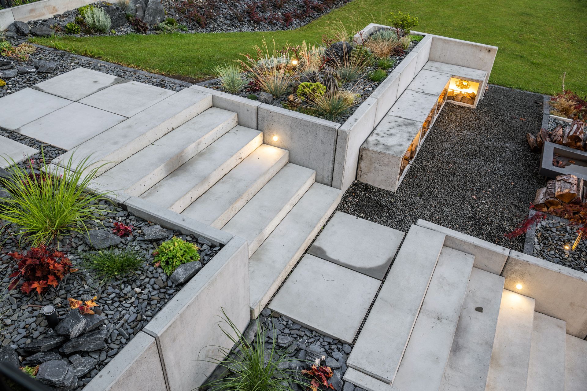 A concrete walkway with stairs and a bench in a garden.