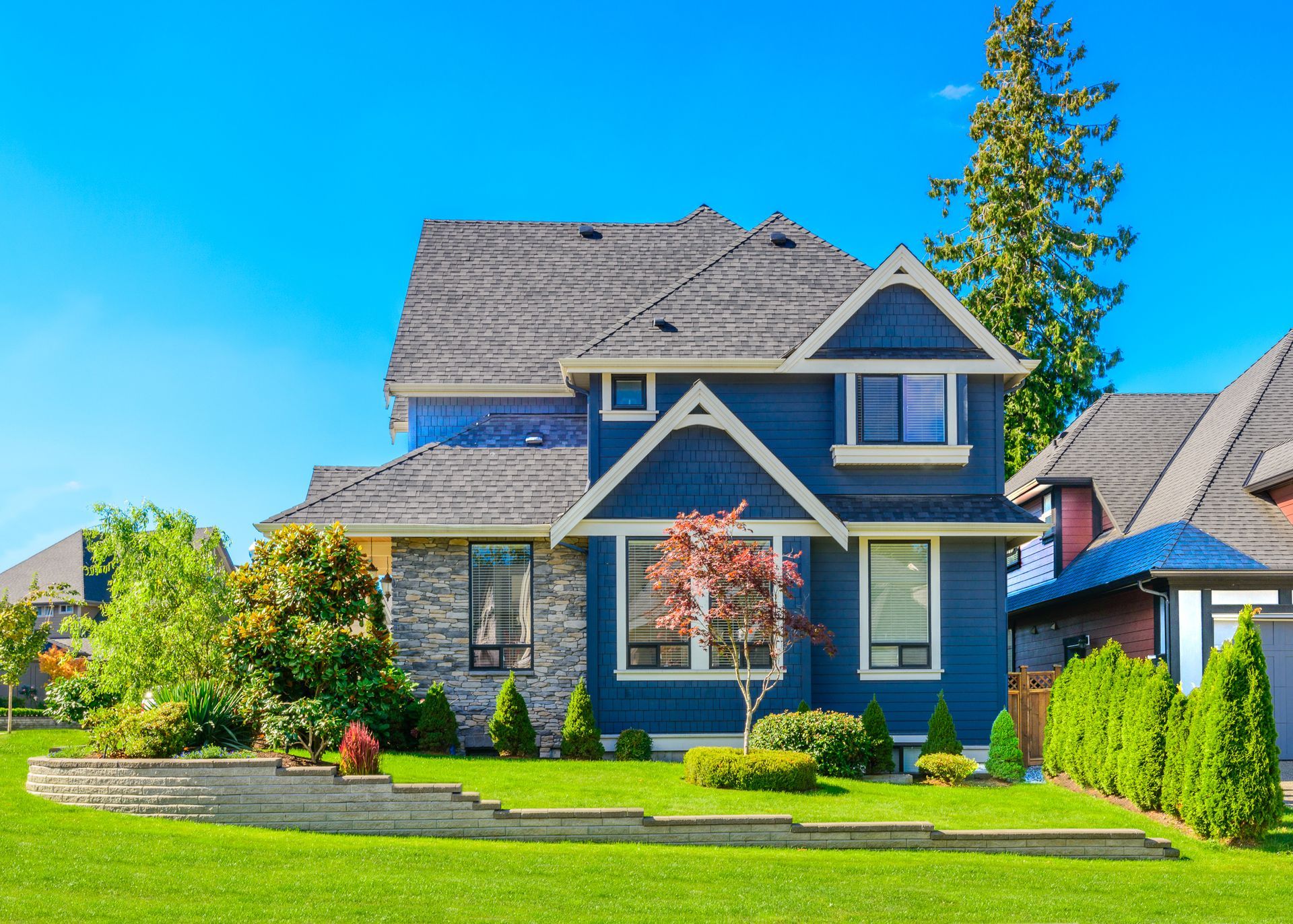 A large blue house with a lush green lawn in front of it.