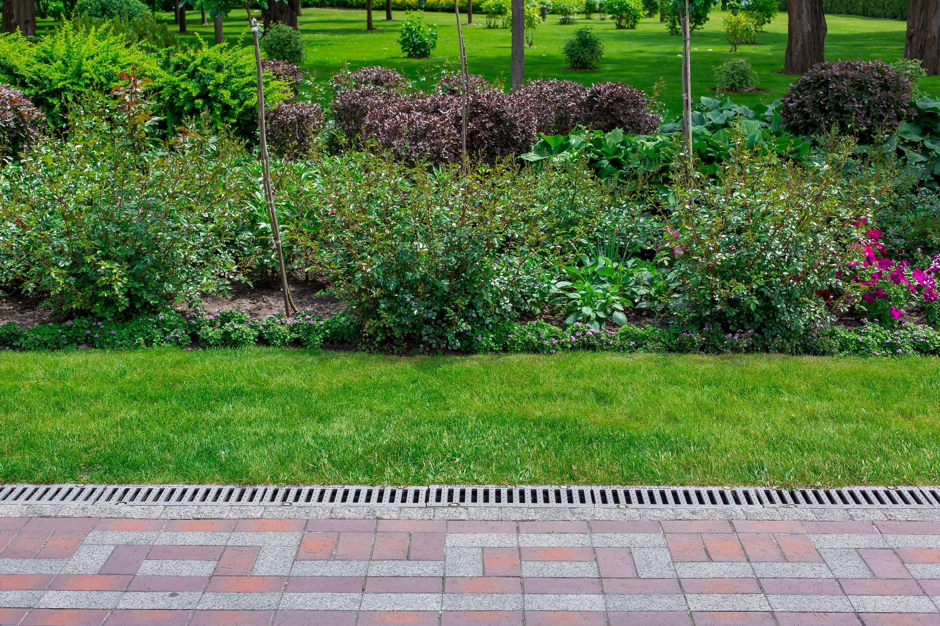 A brick walkway leading to a lush green garden.