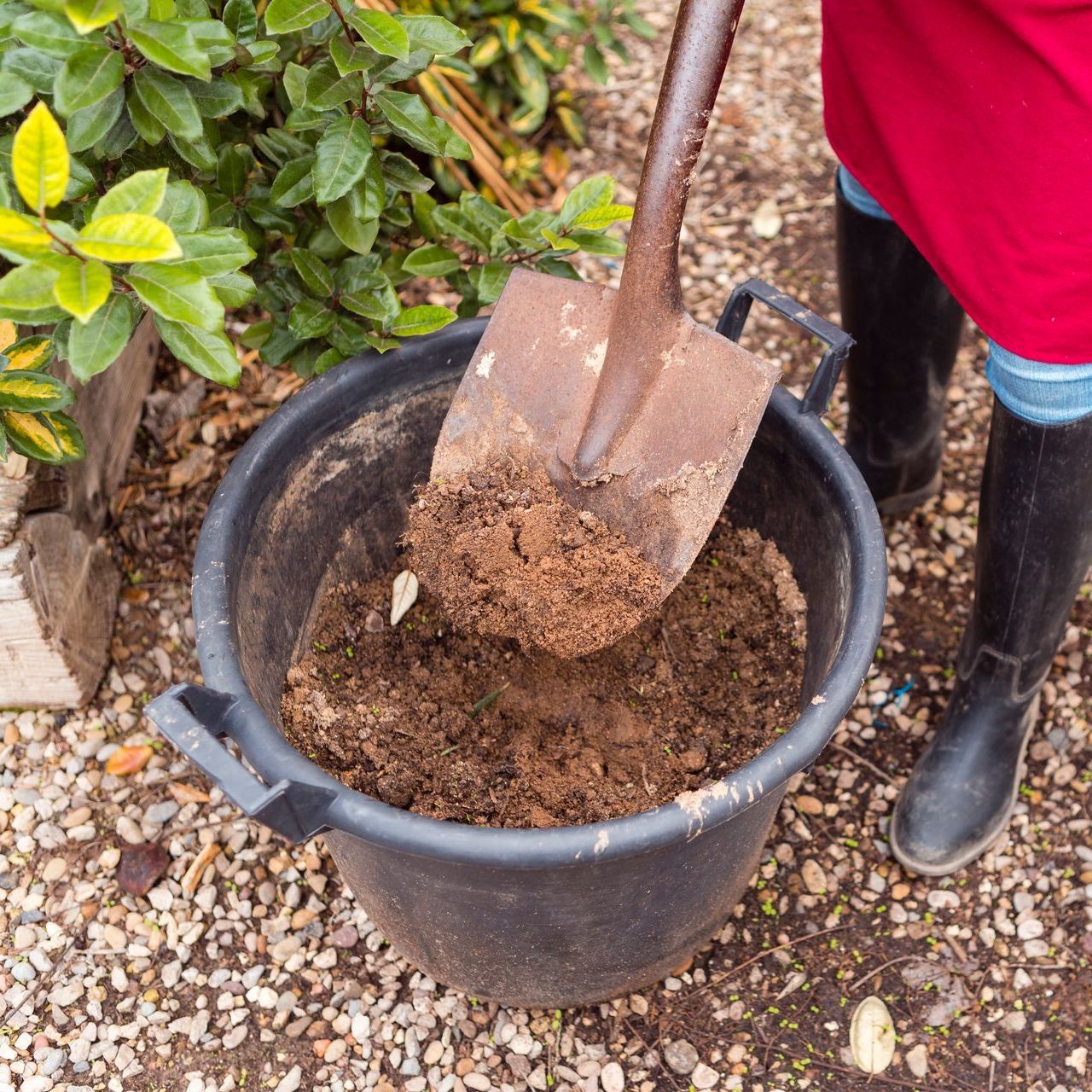 a person is digging in a bucket of dirt with a shovel .