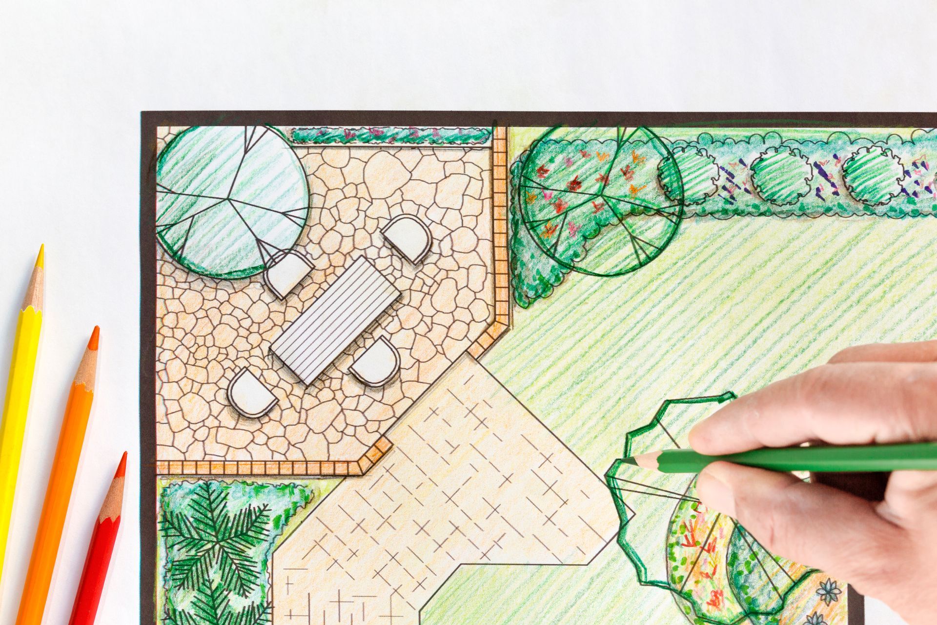 a person is drawing a garden plan with colored pencils .
