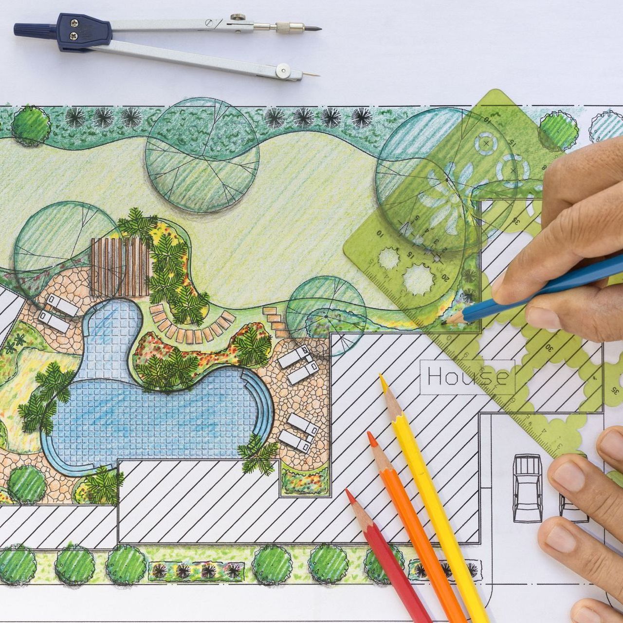 a person is drawing a garden plan with a compass and pencils .