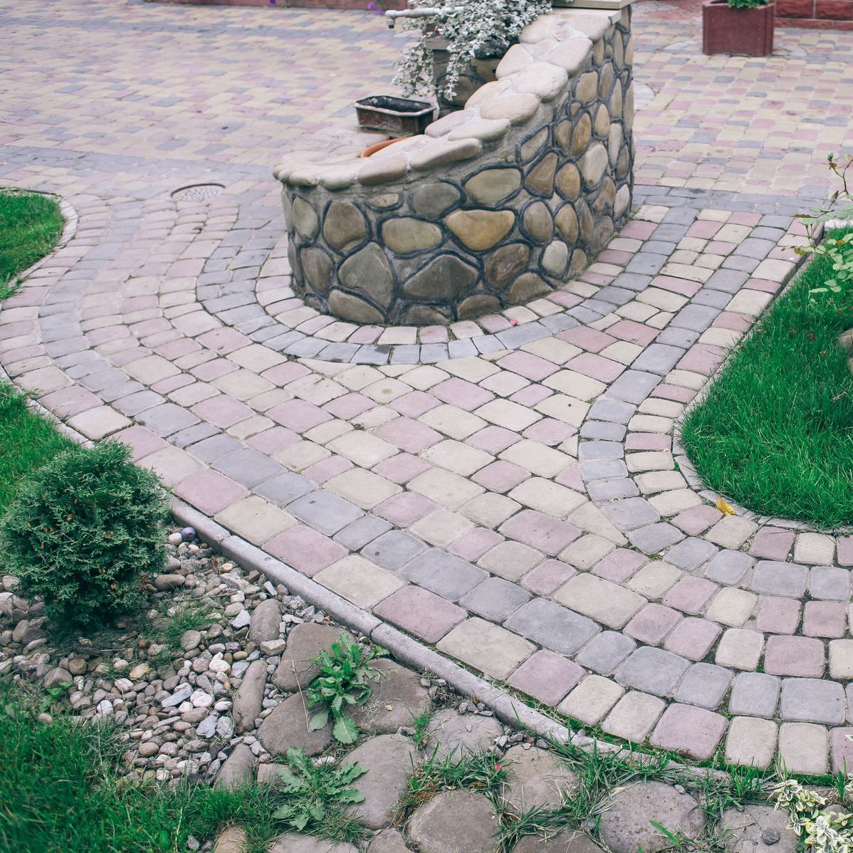 a stone wall surrounds a brick walkway in a garden .