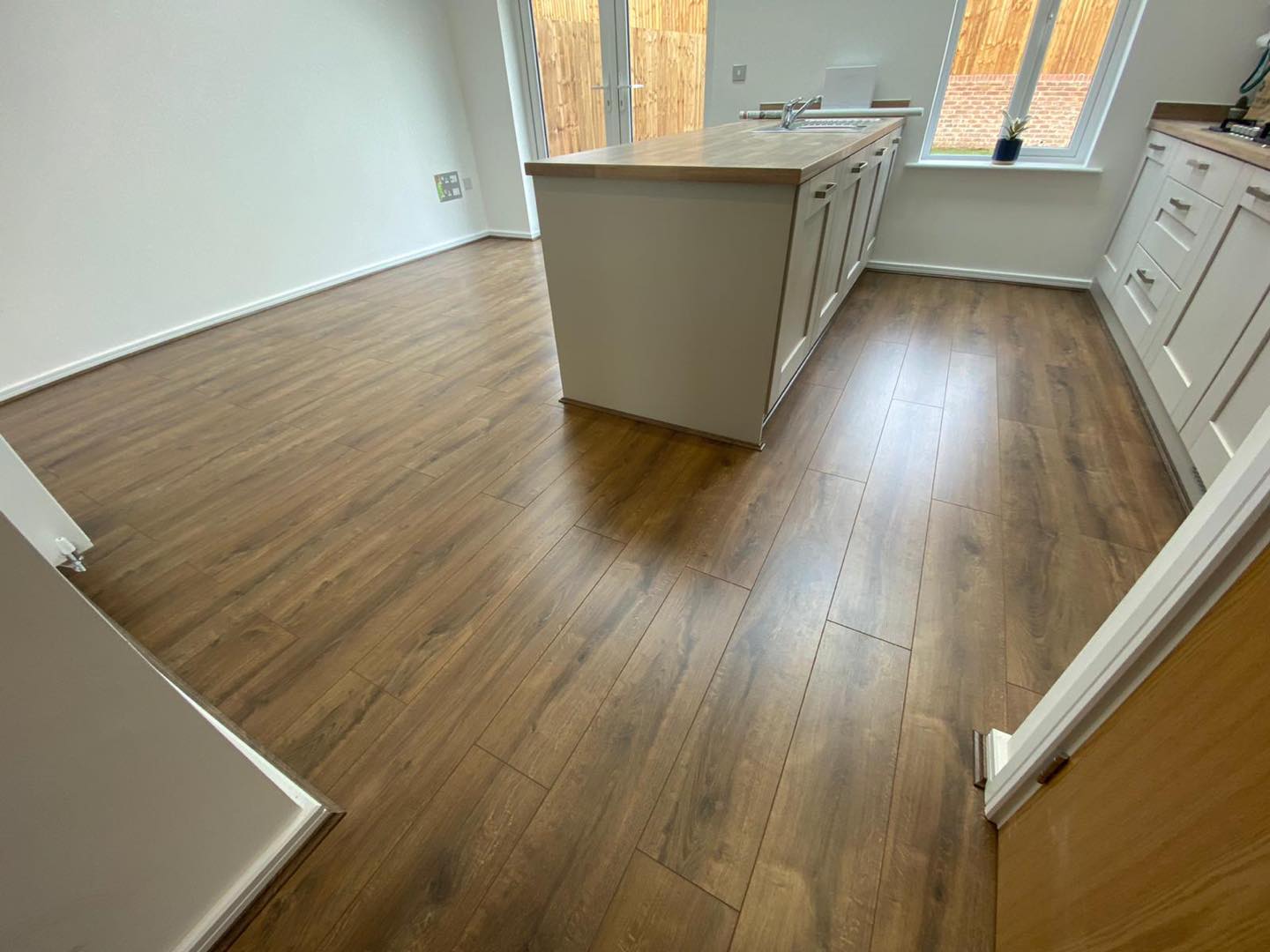 A kitchen with a wooden floor and white cabinets.
