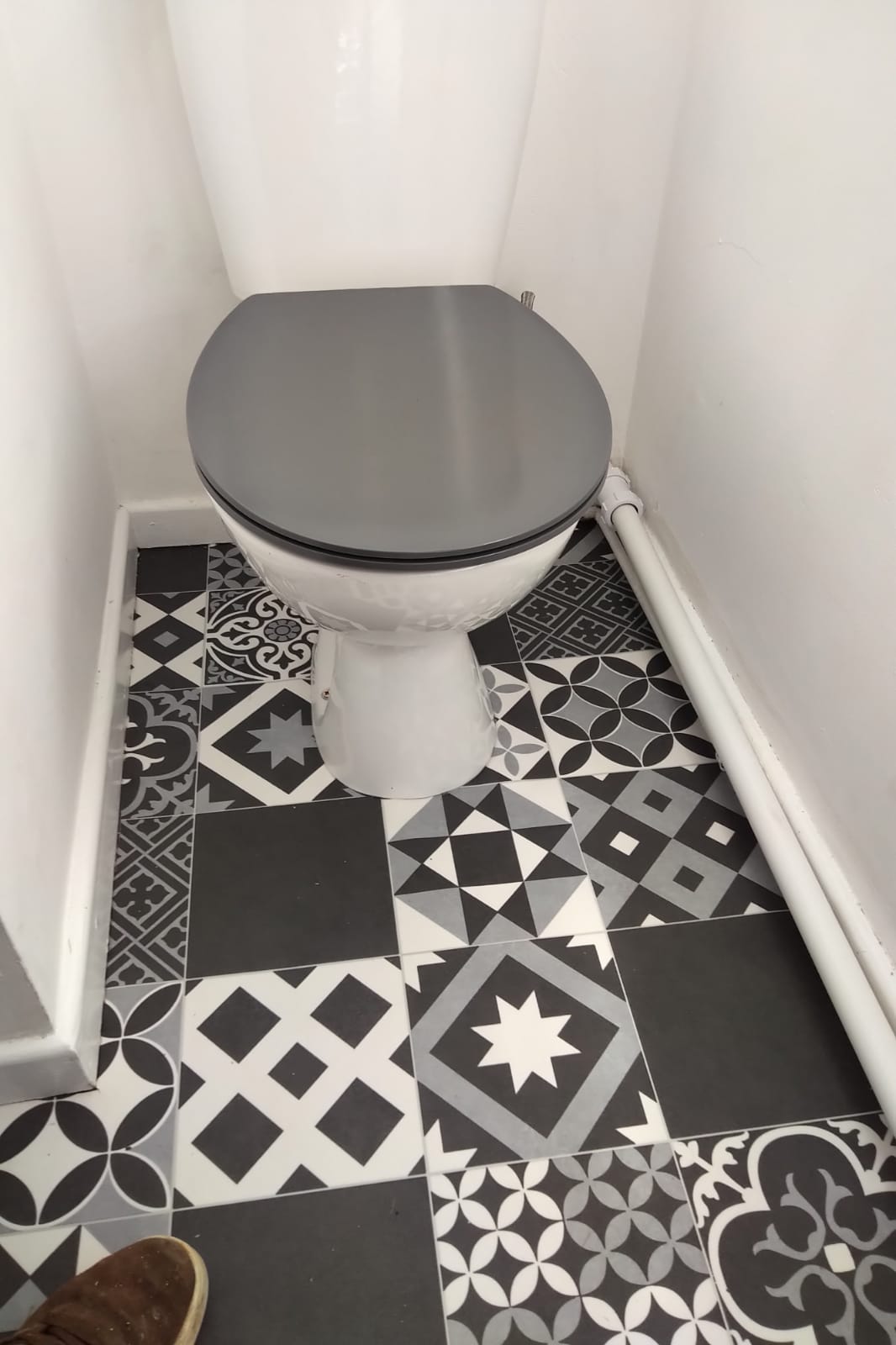 A toilet is sitting on a tiled floor in a bathroom.