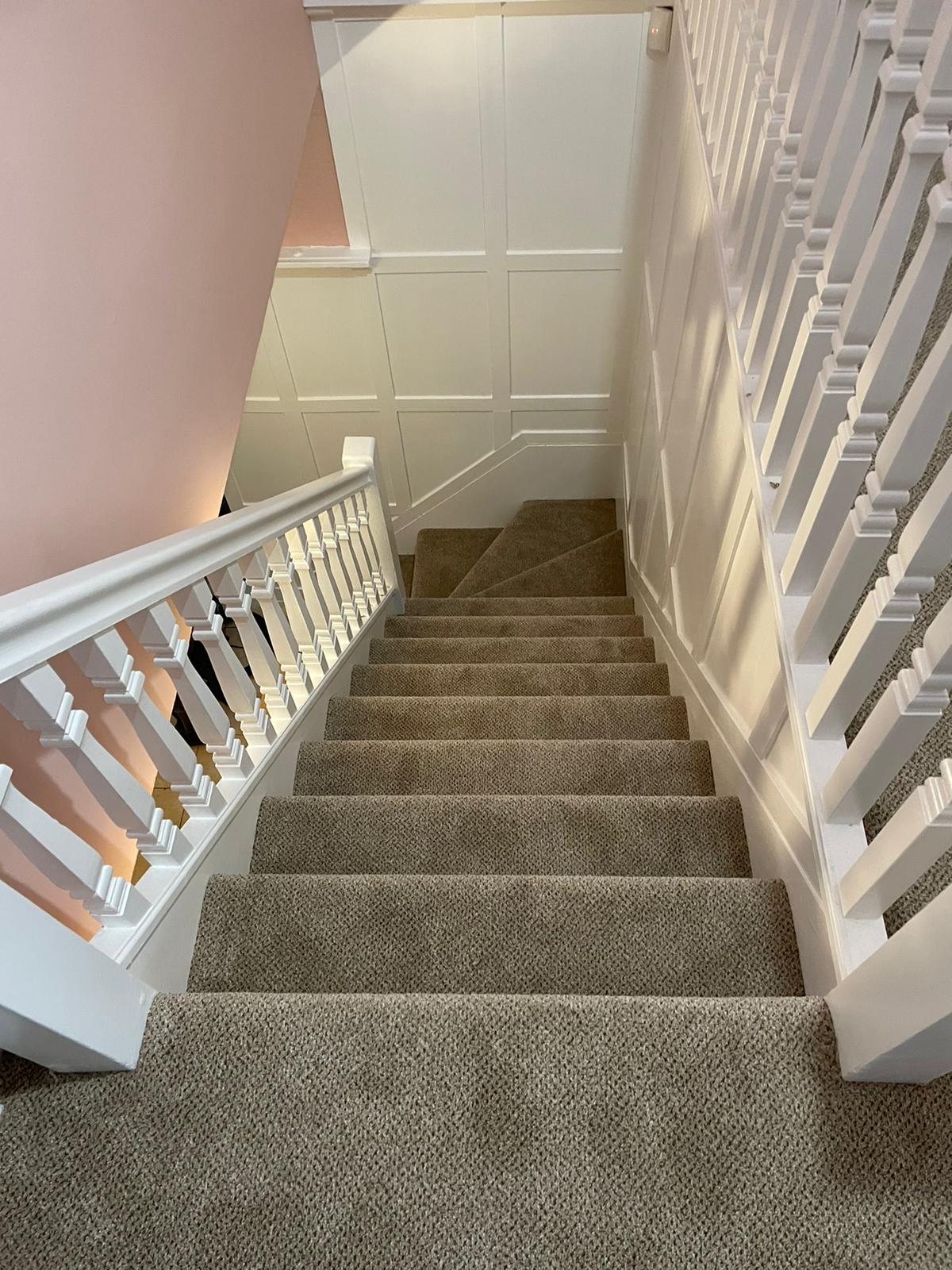 A staircase with carpeted steps and a white railing.