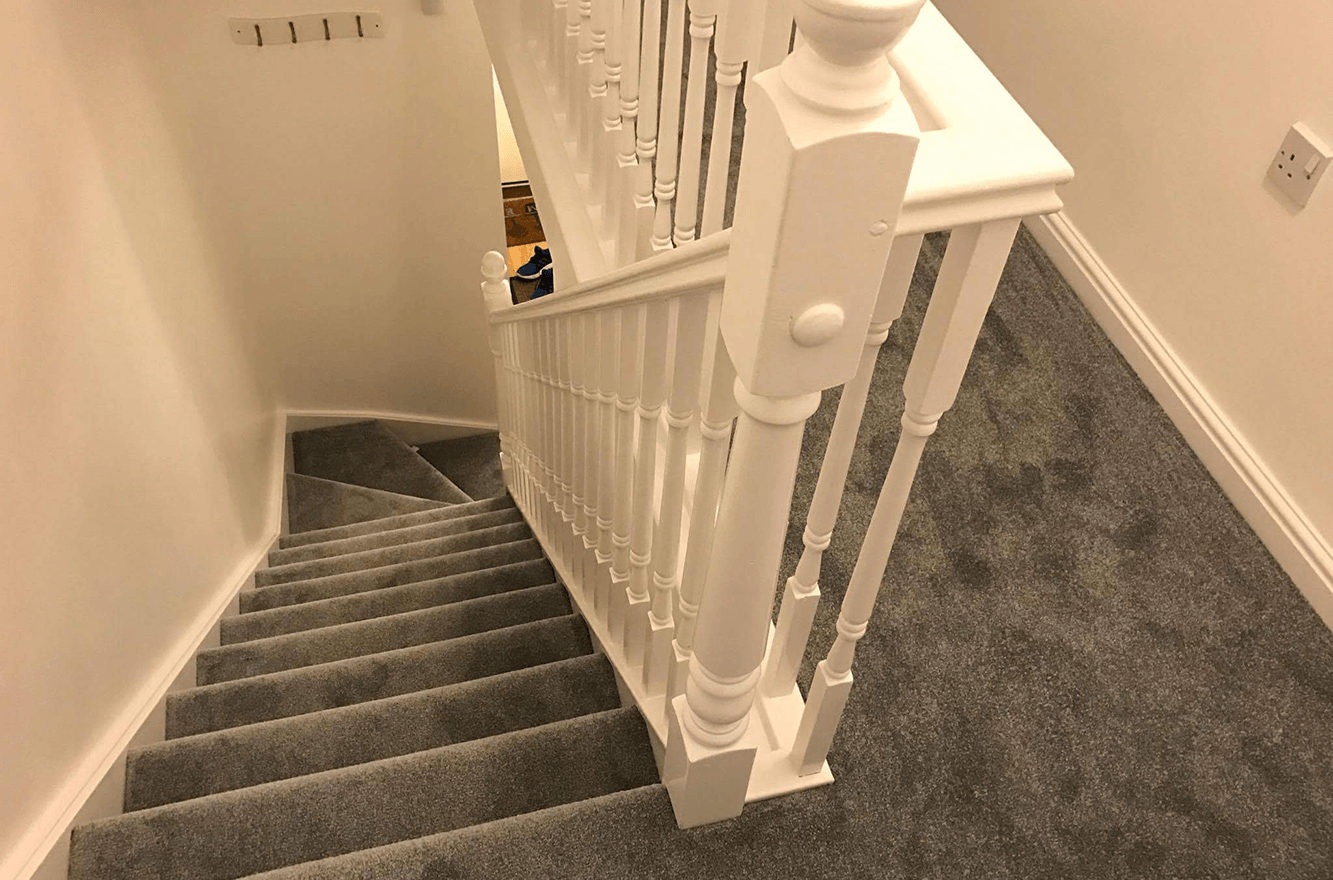 A staircase with a white railing and a gray carpet.