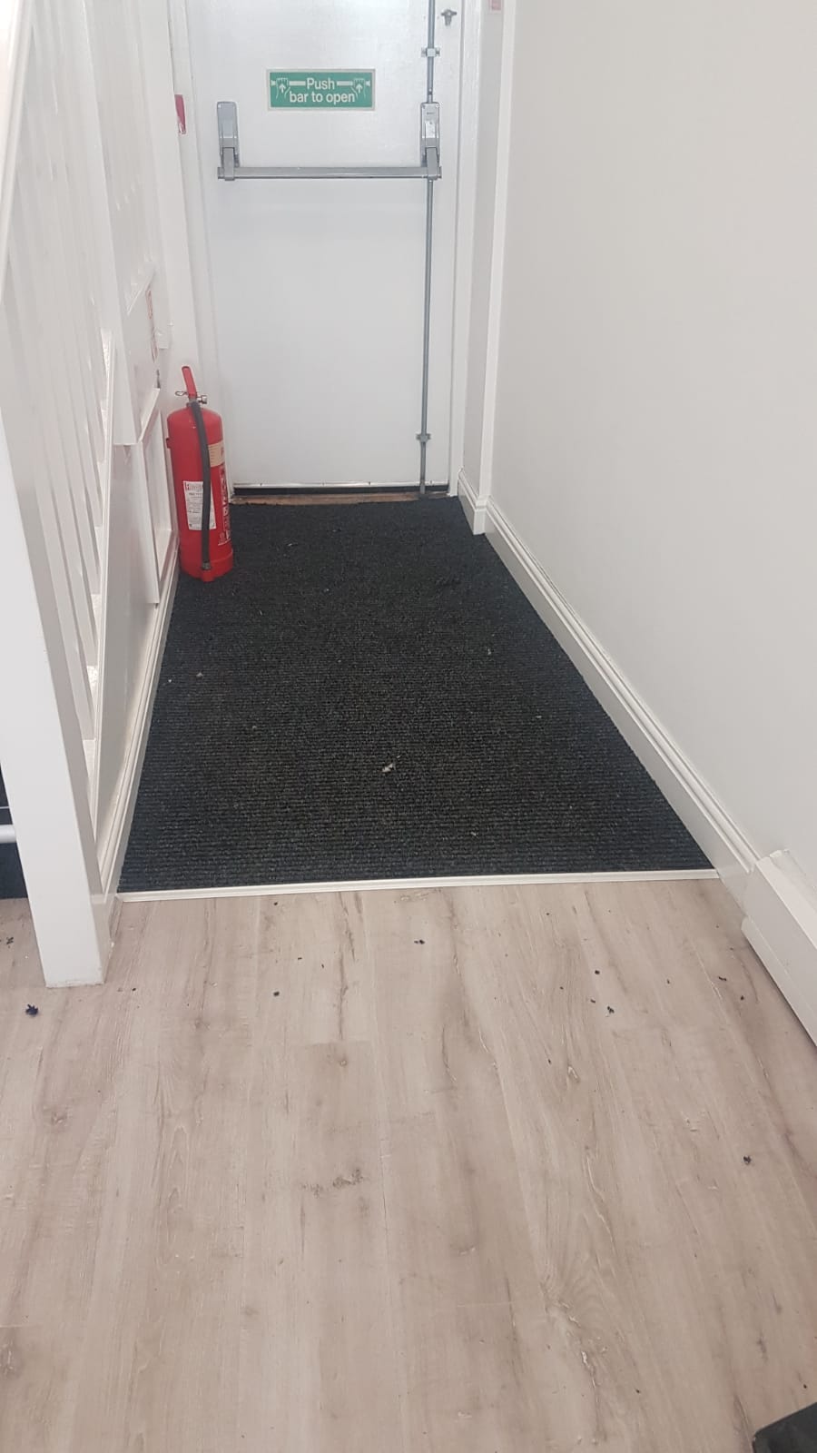 A hallway with a fire extinguisher on the side of the door.