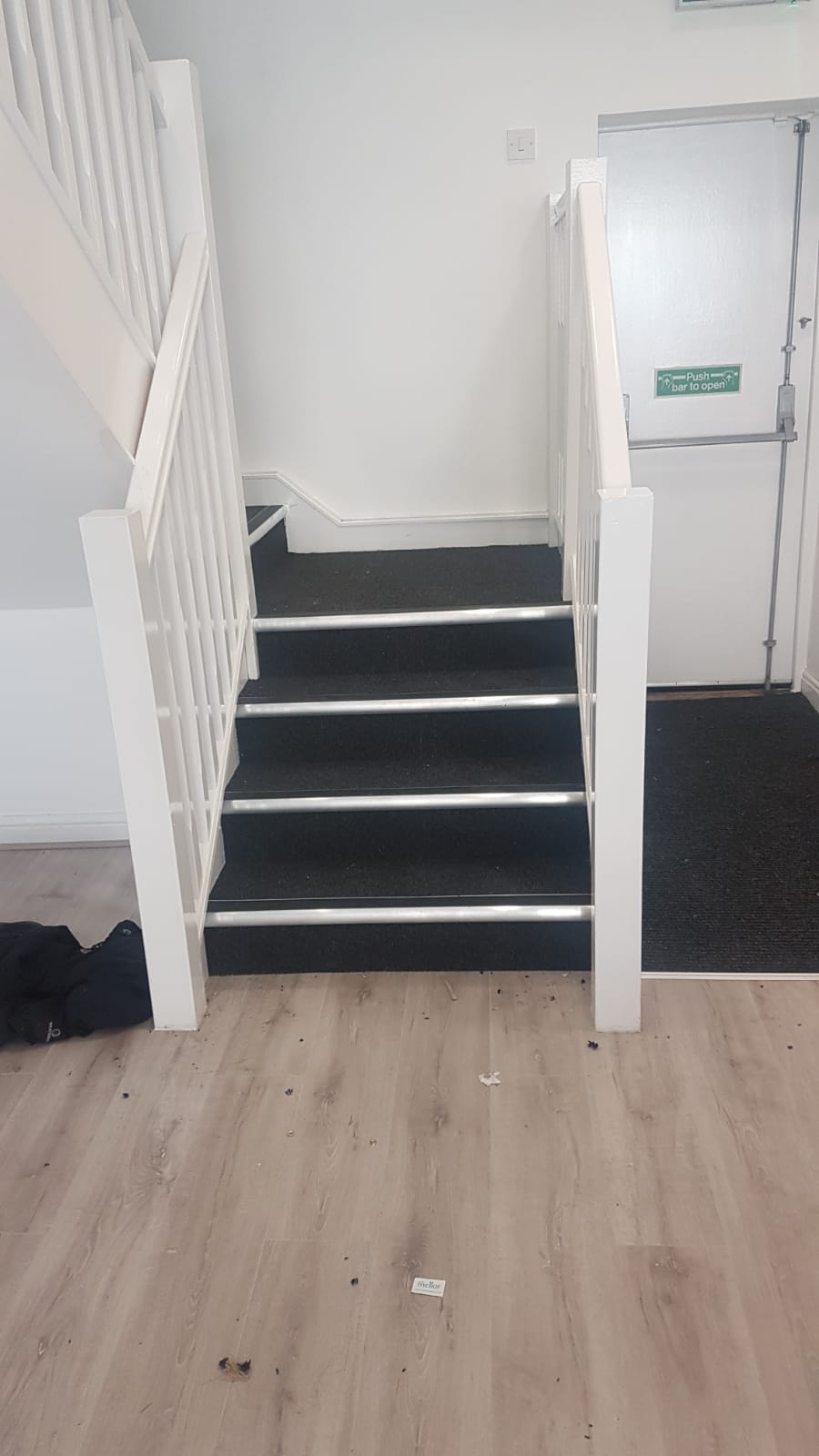 A staircase with black steps and a white railing in a room.