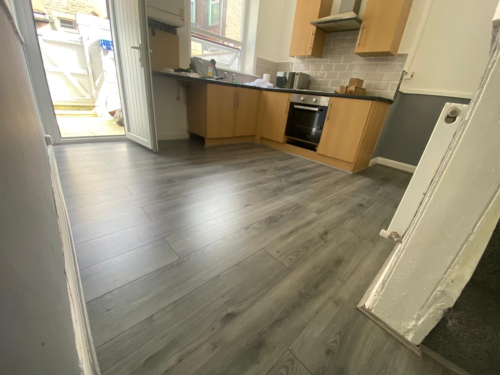 A kitchen with hardwood floors and wooden cabinets.