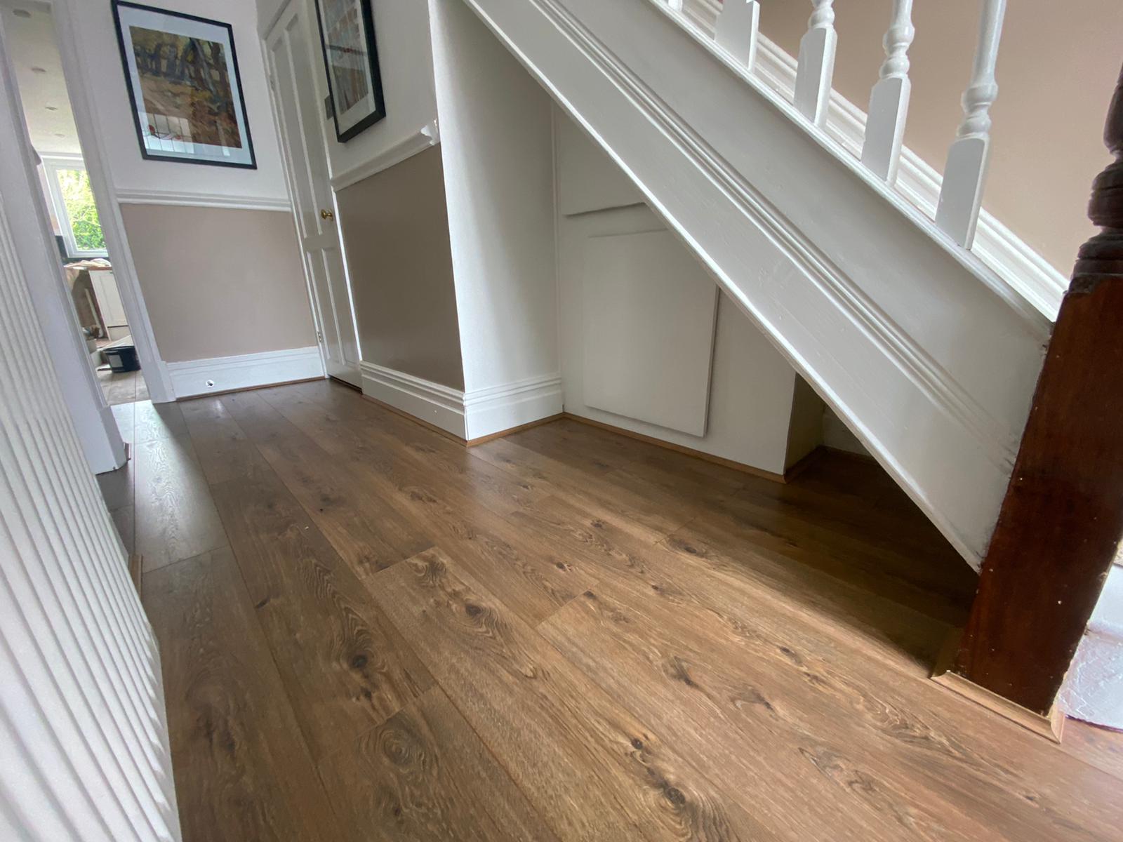 A hallway with hardwood floors and stairs in a house.