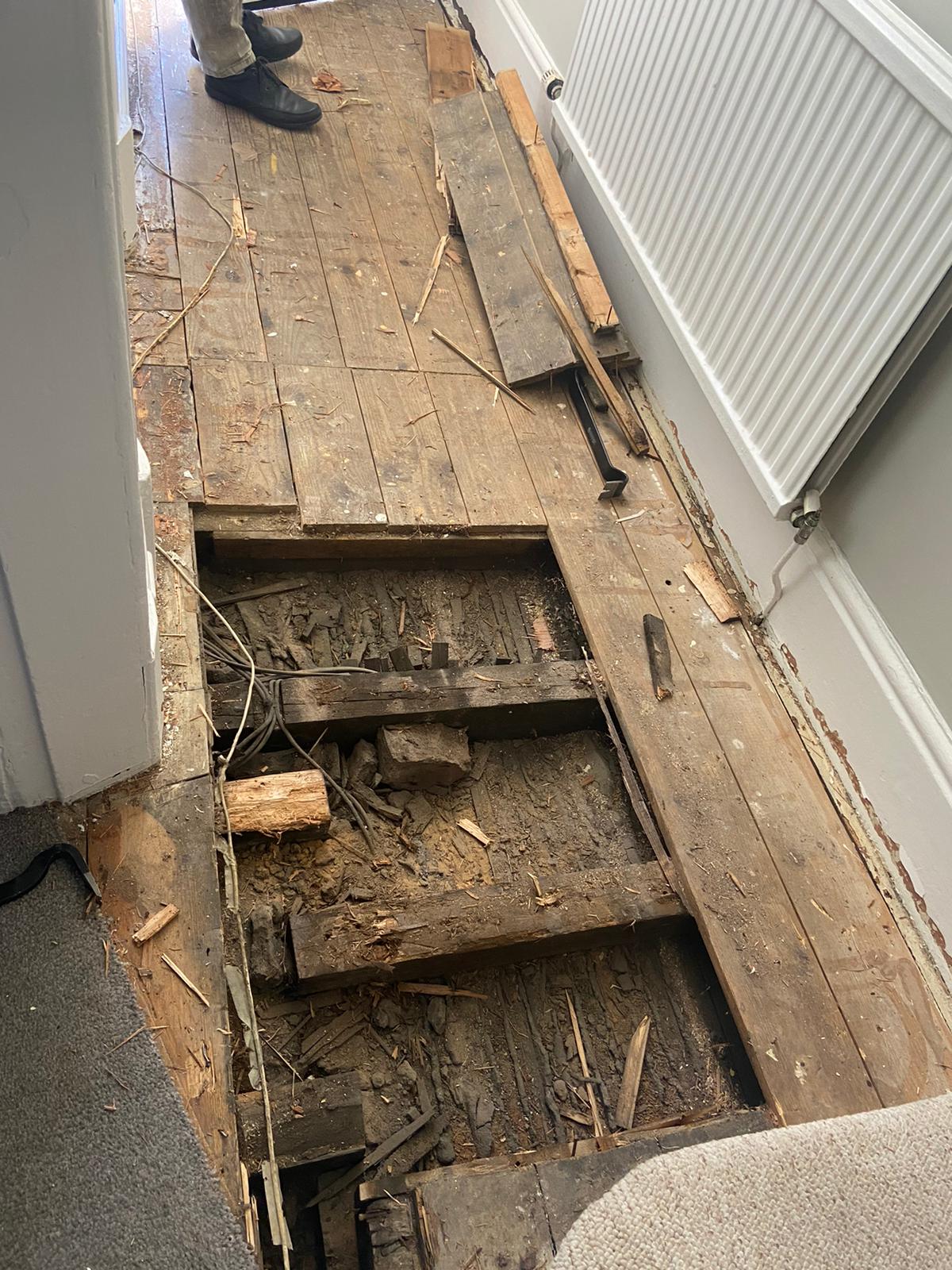 A person is standing on a wooden floor with a hole in it.