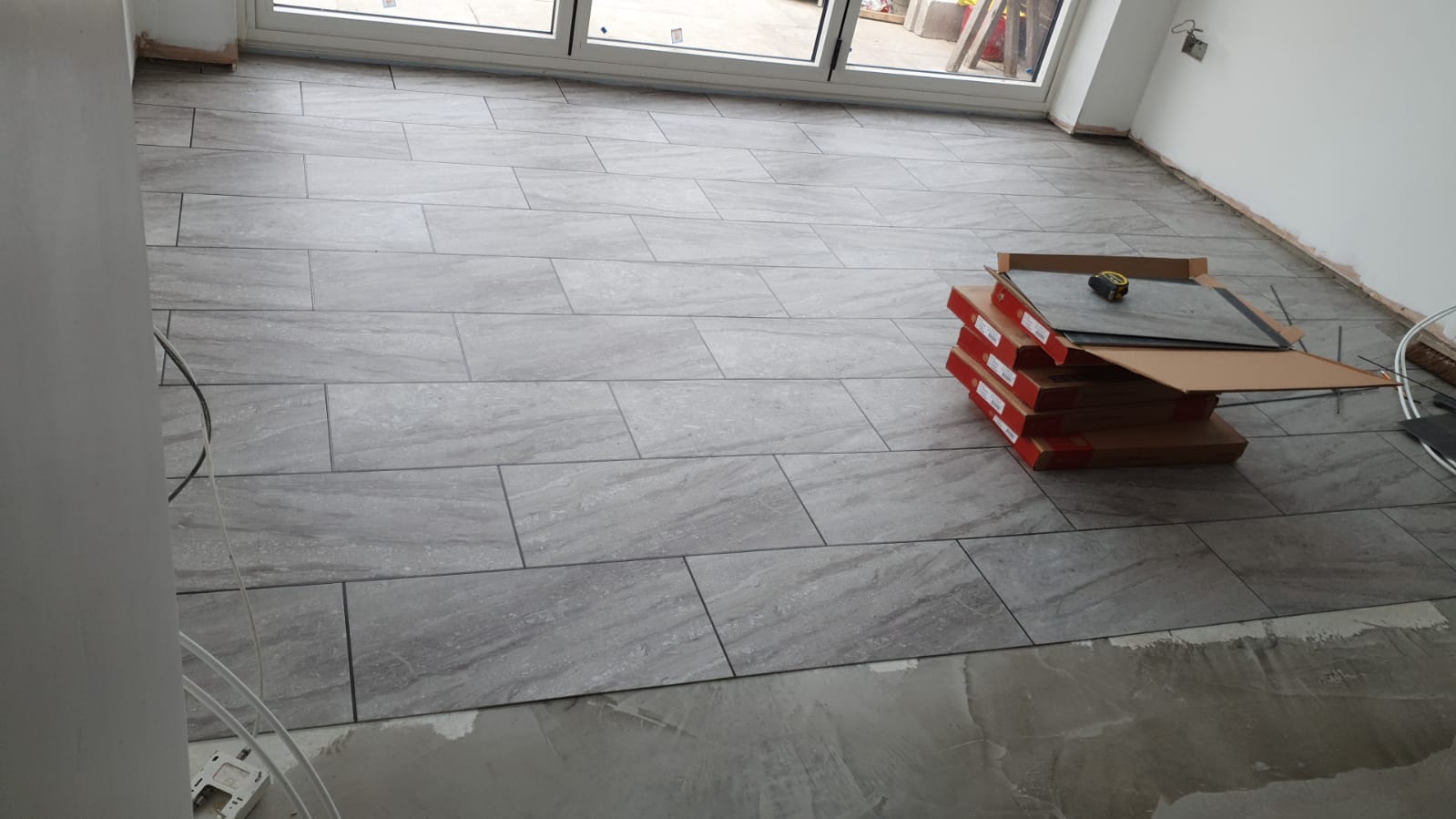 A stack of boxes sitting on top of a tiled floor in a room.