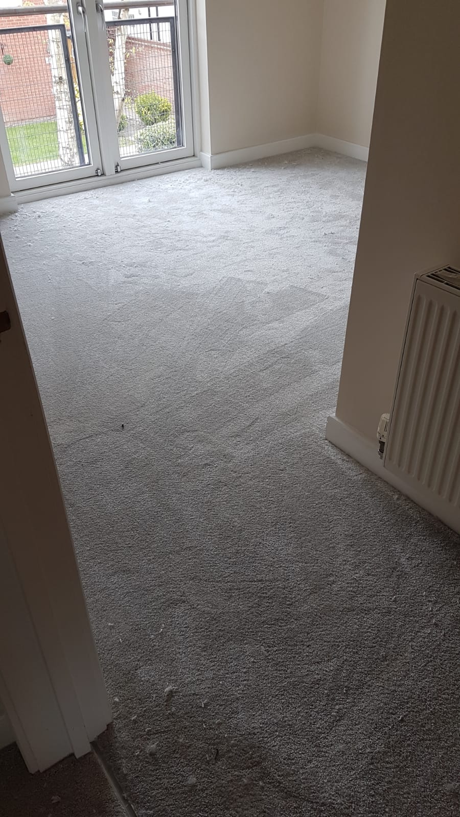 A room with a carpeted floor and a radiator.