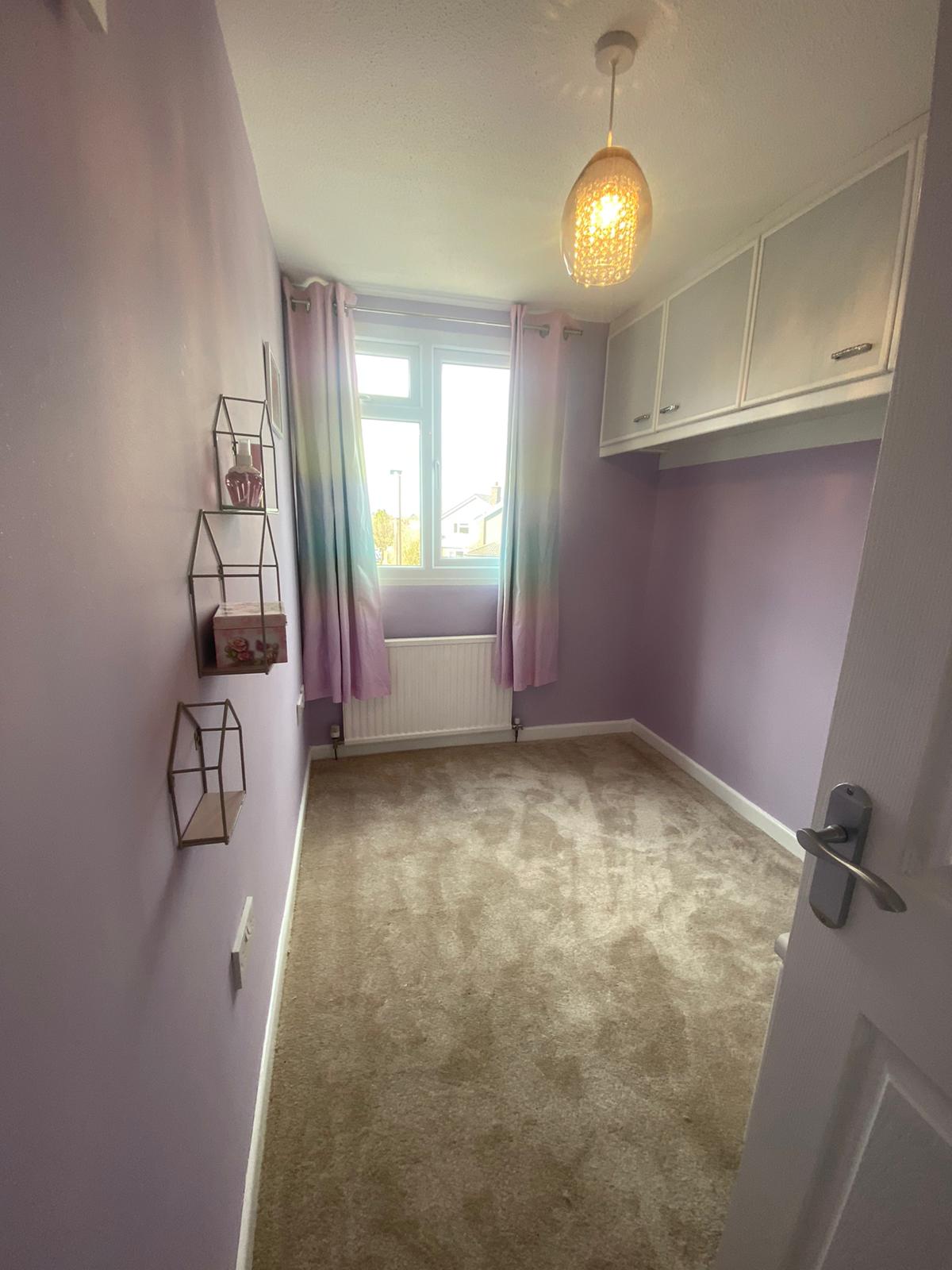 A bedroom with purple walls and a carpeted floor.