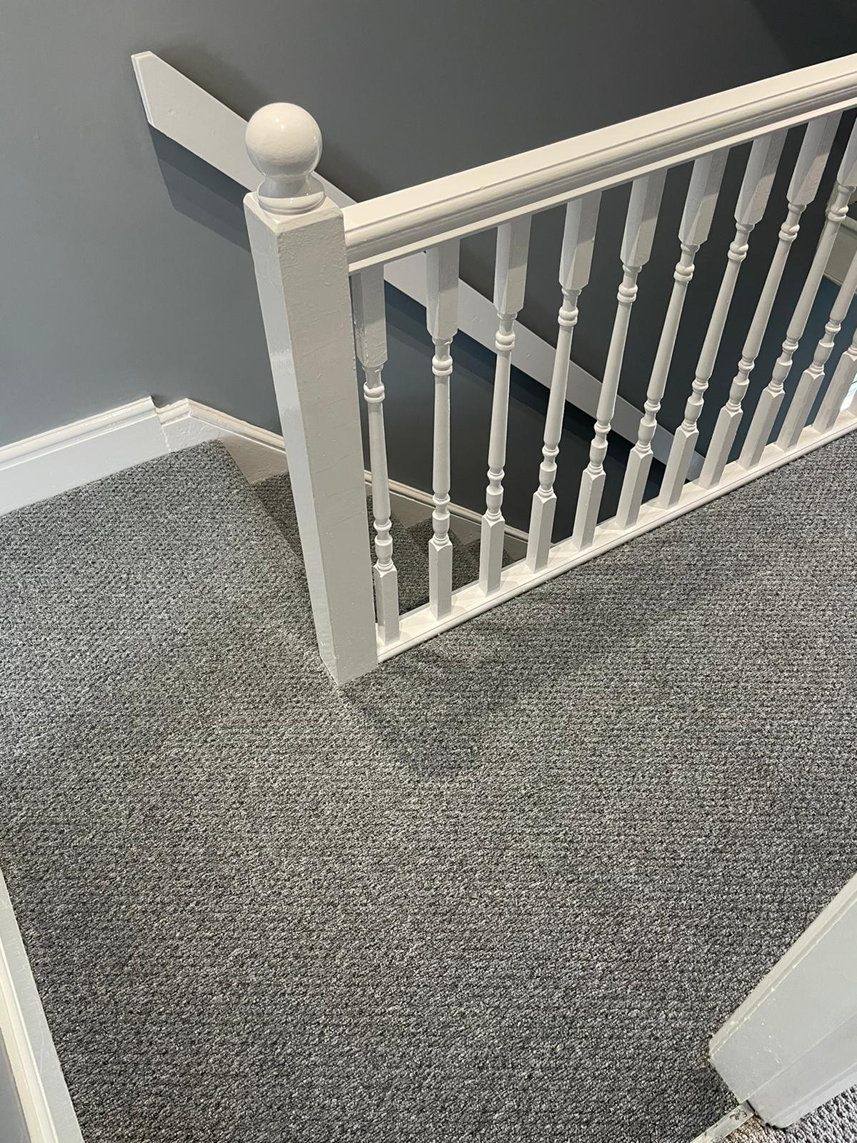 A staircase with a gray carpet and a white railing.